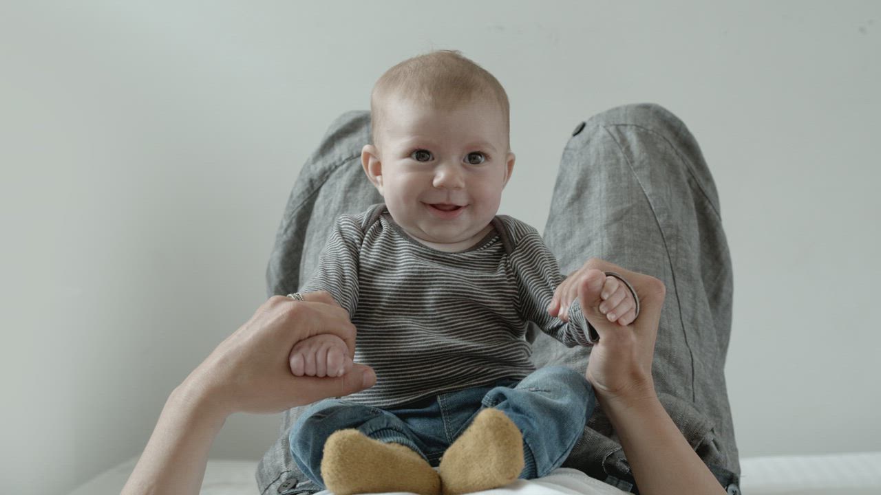 穿着牛仔裤和条纹衬衫的婴儿在母亲的肚子上微笑视频模板素材完整版免费下载