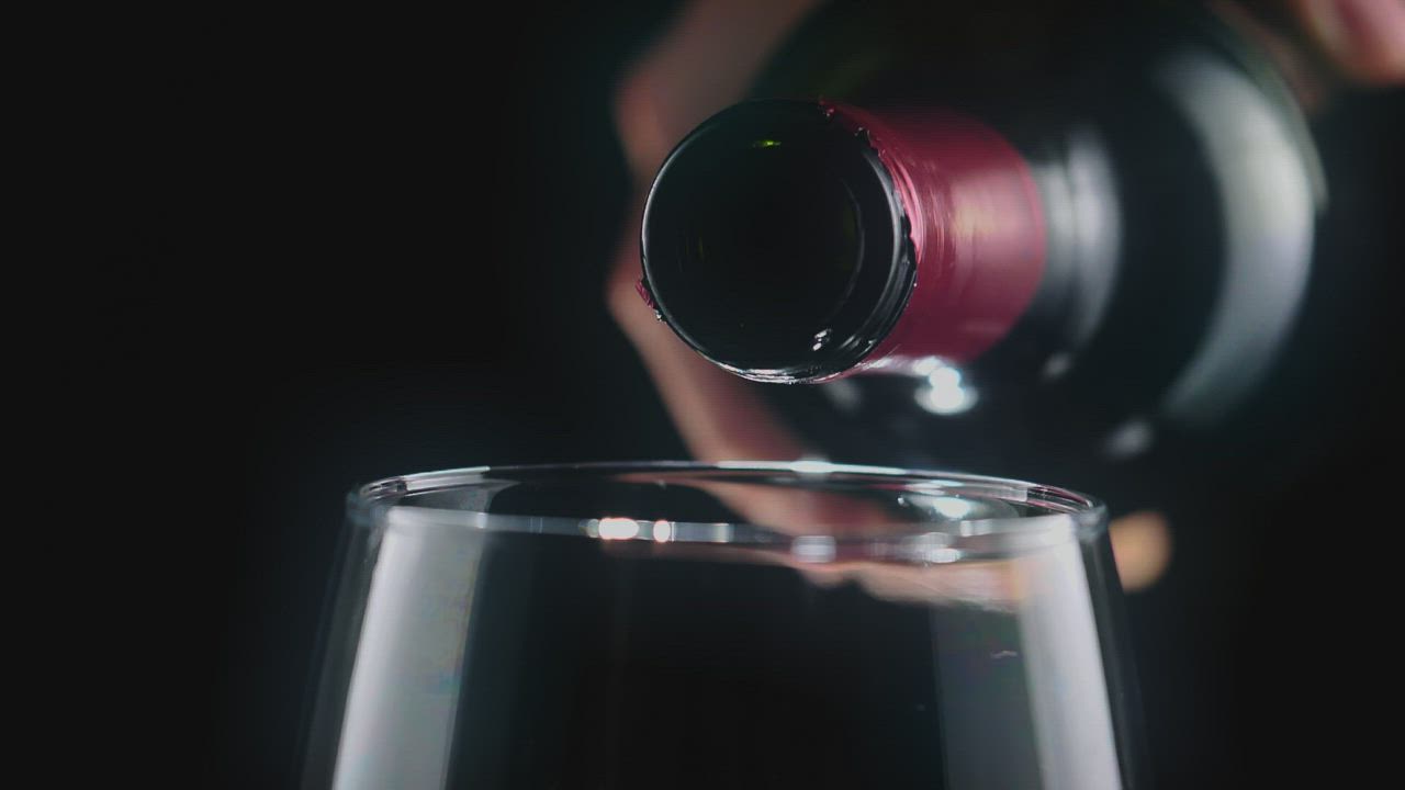 黑色背景上一个人的手直接从瓶子里倒红酒，非常仔细地看着玻璃高脚杯视频模板素材完整版免费下载