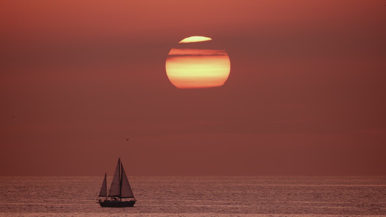 海中的地平线视图日落时分太阳将天空染成暖色而帆船在海中航行背景视频模板素材完整版免费下载