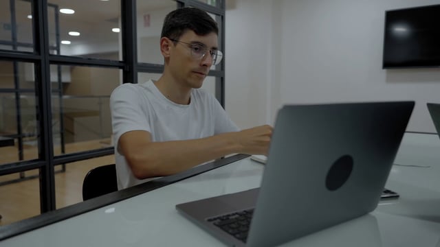 一个年轻人在办公室用笔记本电脑工作的中景镜头视频模板素材完整版免费下载